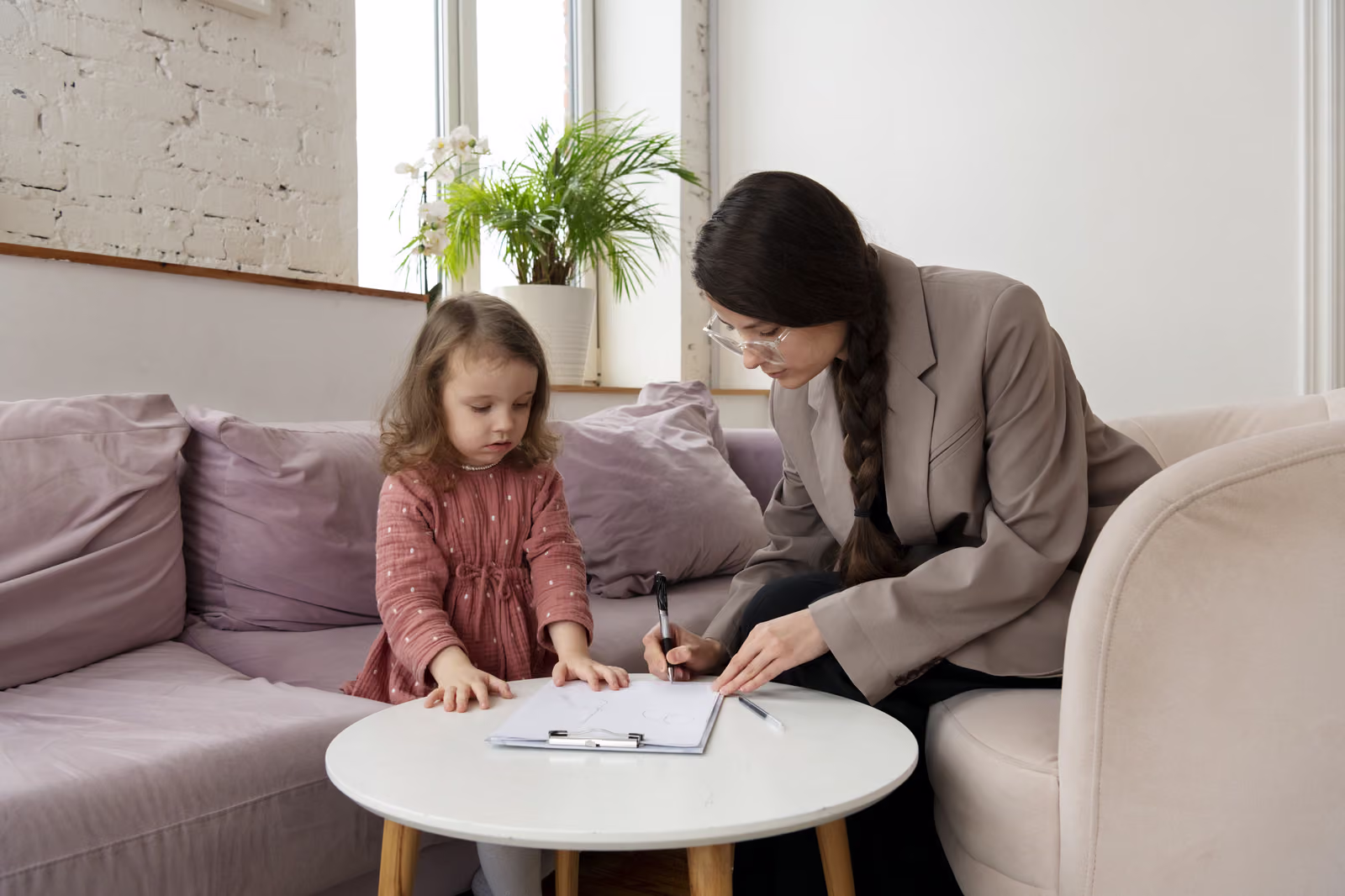 A psychologist working with a young child on a sofa